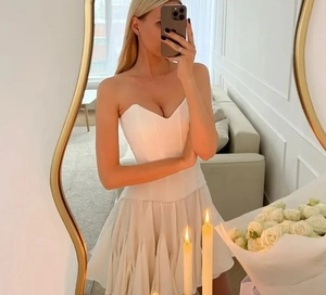 Détail d'une mini robe bustier blanche avec jupe à volants et taille haute cintrée
