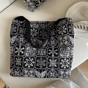Close-up of butterfly embroidery and brand label on black canvas shoulder bag