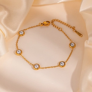 Detail of gold stainless steel pearl bracelet featuring five round pearls on silk fabric