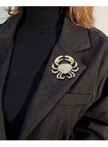 Detailed view of sparkling crystal crab brooch pinned on a black professional blazer