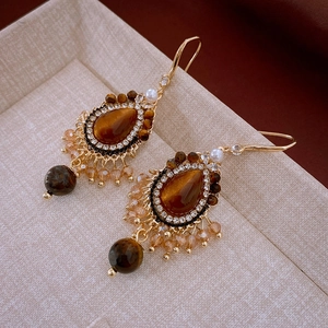 Détail de boucles d'oreilles vintage en or avec pierres œil de tigre et perles champagne