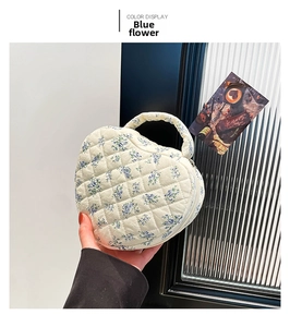 Detail of heart-shaped quilted makeup bag with blue floral pattern and top handle