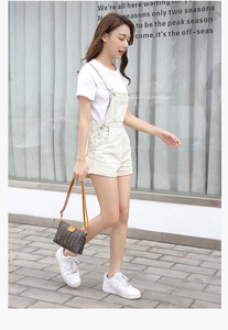 Street style shot of a woman with a dark brown printed mini handbag and denim overalls