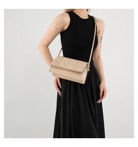 Detail of beige quilted crossbody bag with diamond patterns and knotted shoulder strap