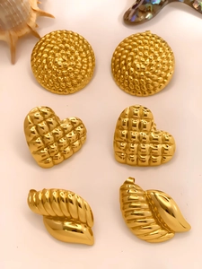 Close-up of geometric gold earrings featuring quilted heart and textured spiral designs