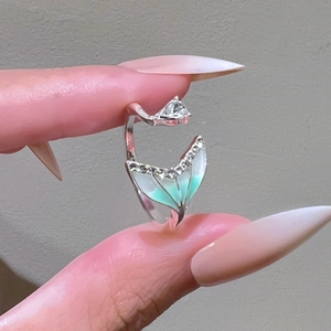 Detailed shot of mermaid tail ring with green enamel, zircons and clear gemstone