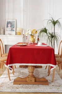 Detail of red cotton tablecloth featuring elegant white lace edges on a wooden dining table