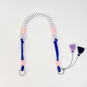 Primer plano de una correa de bolso de nailon trenzado colorido con anillos metálicos y borlas