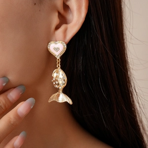 Detail of gold heart and fish earrings with pink enamel and sparkling rhinestones on model