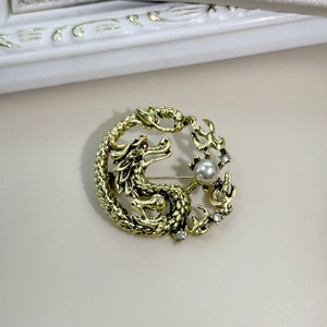 Close-up of golden dragon brooch with pearl accents and sparkling rhinestones