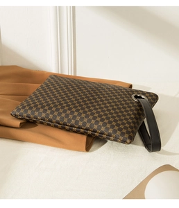 Detail of crocodile pattern clutch with gold geometric print and metal ring clasp