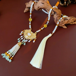 Detail of vintage Chinese pendant necklace with pearls and jade on rustic wood