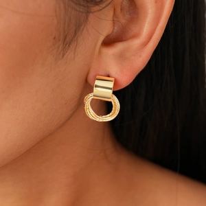 Detail of geometric gold earrings with interlocking rings on model ear