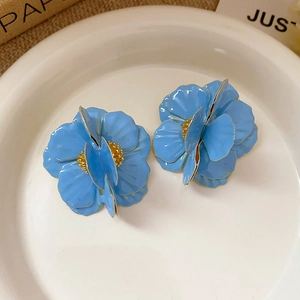 Detail of blue 3D flower earrings with golden core on a white ceramic tray