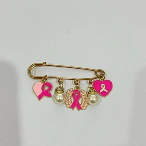 Détail de la broche ruban rose avec des cœurs en émail et des perles décoratives