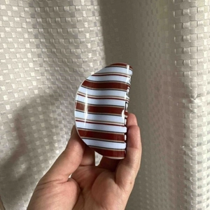 Detail of red and brown striped hair claw clip made of durable acrylic material