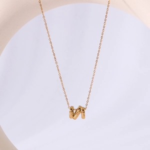 Minimalist 18K gold plated hollow letter N titanium steel necklace on a white ring stand