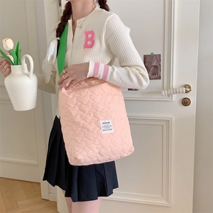 Detail of pink heart-quilted tote bag featuring vibrant green shoulder straps