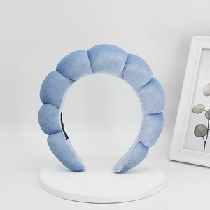 Close-up of light blue velvet puffy headband with soft wavy cloud shape and inner label
