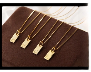 Macro shot of gold square letter pendants E F G H on a luxury brown velvet display case