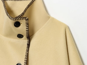 Close-up of beige wool coat featuring brown hand-stitched edges and large black buttons