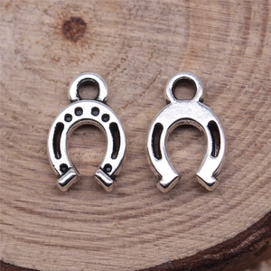 Silver horseshoe pendants for DIY necklaces on a natural wood surface texture