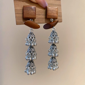 Détail de boucles d'oreilles bohèmes en bois avec cloches creuses en argent antique