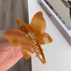 Detailed macro view of acetate amber bow hair claw with elegant marble texture and spring