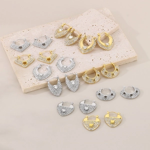 Détail de boucles d'oreilles en forme de cœur avec strass dorés et argentés sur pierre
