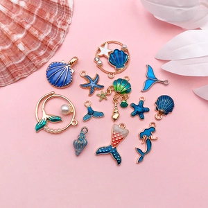 Macro shot of 12 ocean-themed enamel charms including mermaids, seashells and starfish
