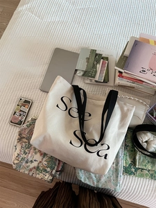 Detail view of large canvas tote bag with See Sea text print on striped bedding