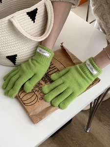 Detailed view of green knitted winter gloves with soft ribbed cuffs and thick warm texture