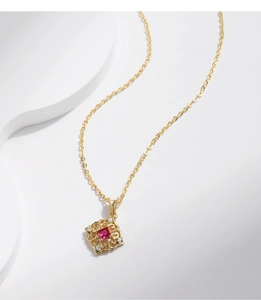 Macro detail of gold S925 sterling silver necklace with red gemstone and floral pattern