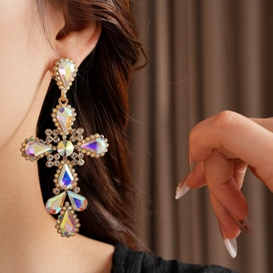 Detail of vintage gold cross earrings with colorful rhinestones worn by a model