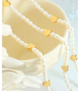 Close-up of freshwater pearl necklace with heart pendant draped on a ceramic bowl