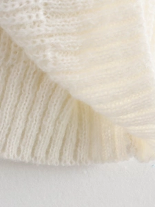 Makroaufnahme von weißem Strickstoff mit weicher Textur und gerippten Strickdetails des Pullovers