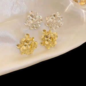 Elegant hollow floral stud earrings in gold and silver finish on silk fabric