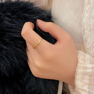 Detailed close-up of a minimalist wavy gold ring worn against a stylish lace sleeve