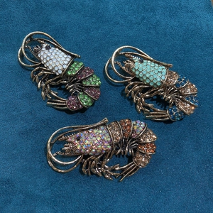 Macro shot of lobster brooches with colorful rhinestones on gold base over velvet