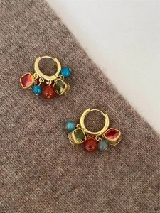 Macro detail of gold hoop earrings featuring zircon, agate beads and colorful gemstones