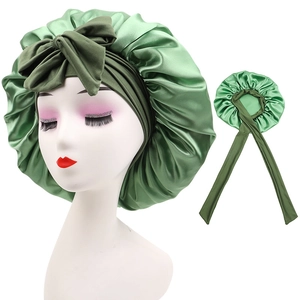 Detail of green satin sleeping bonnet with elastic edge and large decorative bow knot