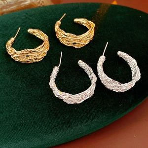 Detail of 18K gold and silver plated C-shape earrings with twisted texture on velvet
