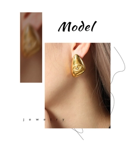 Macro view of gold-plated teardrop earrings with embossed eye design and zircon