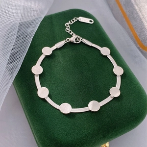 Bracelet chaîne serpent argentée avec disques ronds sur une boîte à bijoux en velours vert