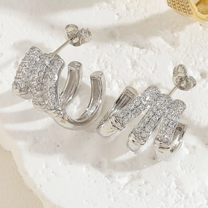 Macro view of silver C-shaped multi-layer stud earrings with zircon stones and silver finish