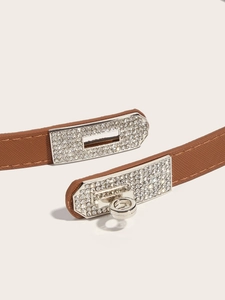 Close-up of brown leather belt with luxury metal lock buckle and sparkling rhinestones