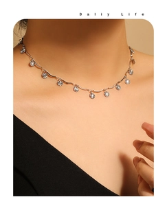Detail of silver sunburst pendant necklace with wave chain on model neck
