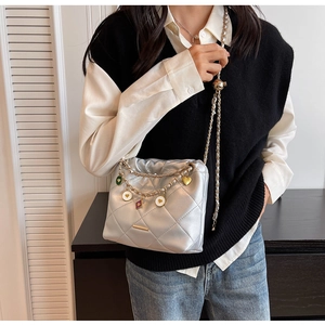 Détail du sac seau matelassé argenté avec charms cœurs colorés et bandoulière chaîne