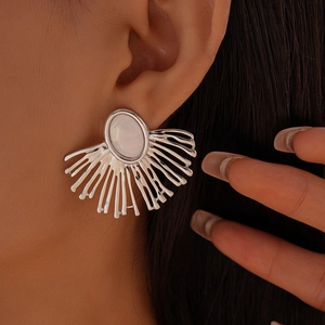 Detailed close-up of a large silver fan-shaped earring with a white moonstone-like inlay