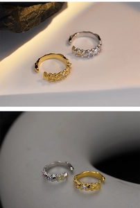 Close-up of gold and silver ear cuffs with colorful zircons and wavy metal texture